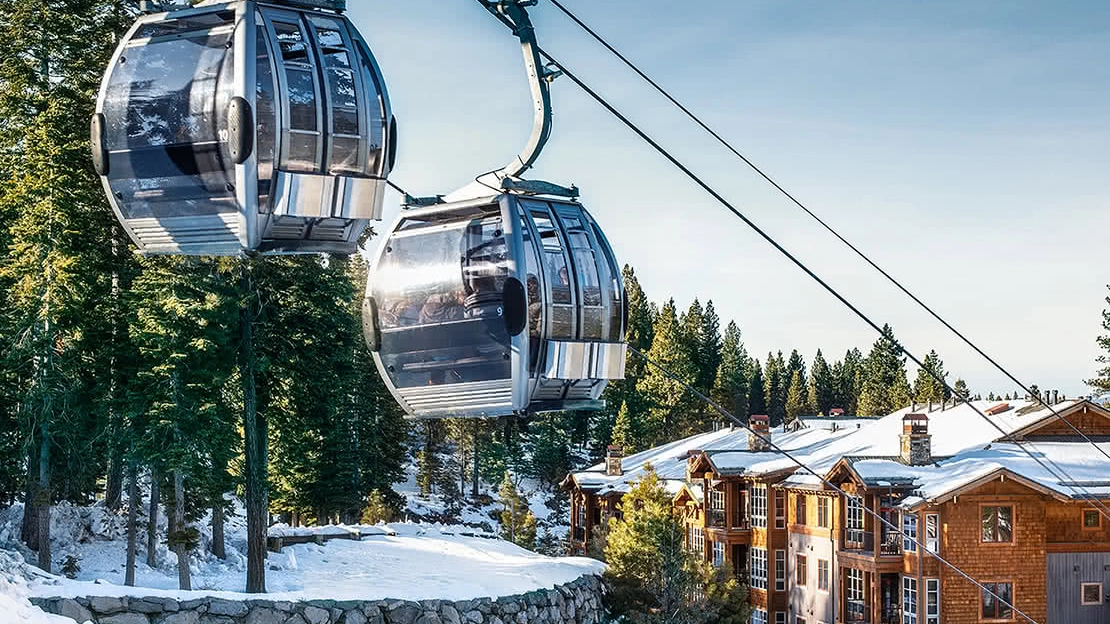 Gondola taking skiers up the hill with the resort and evergreens in the background