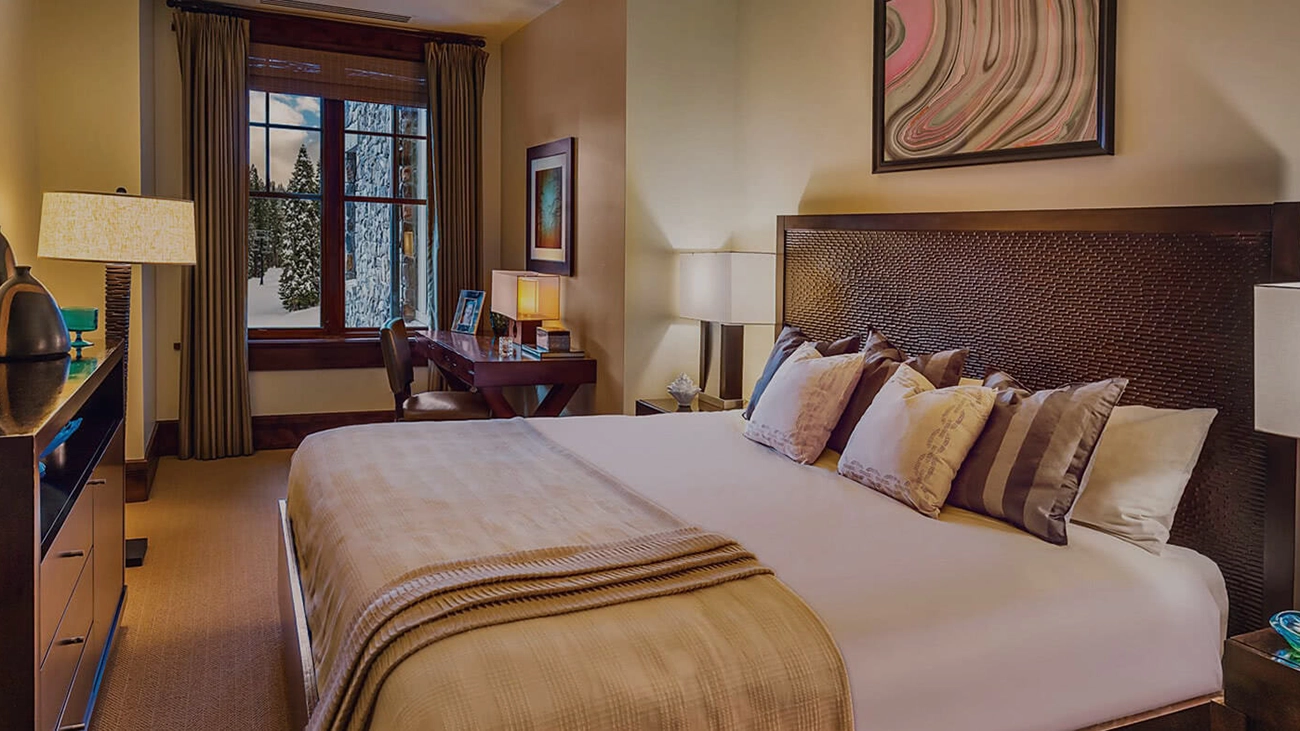 Interior of villa with bed, desk, and dresser, with window view of snowy slopes