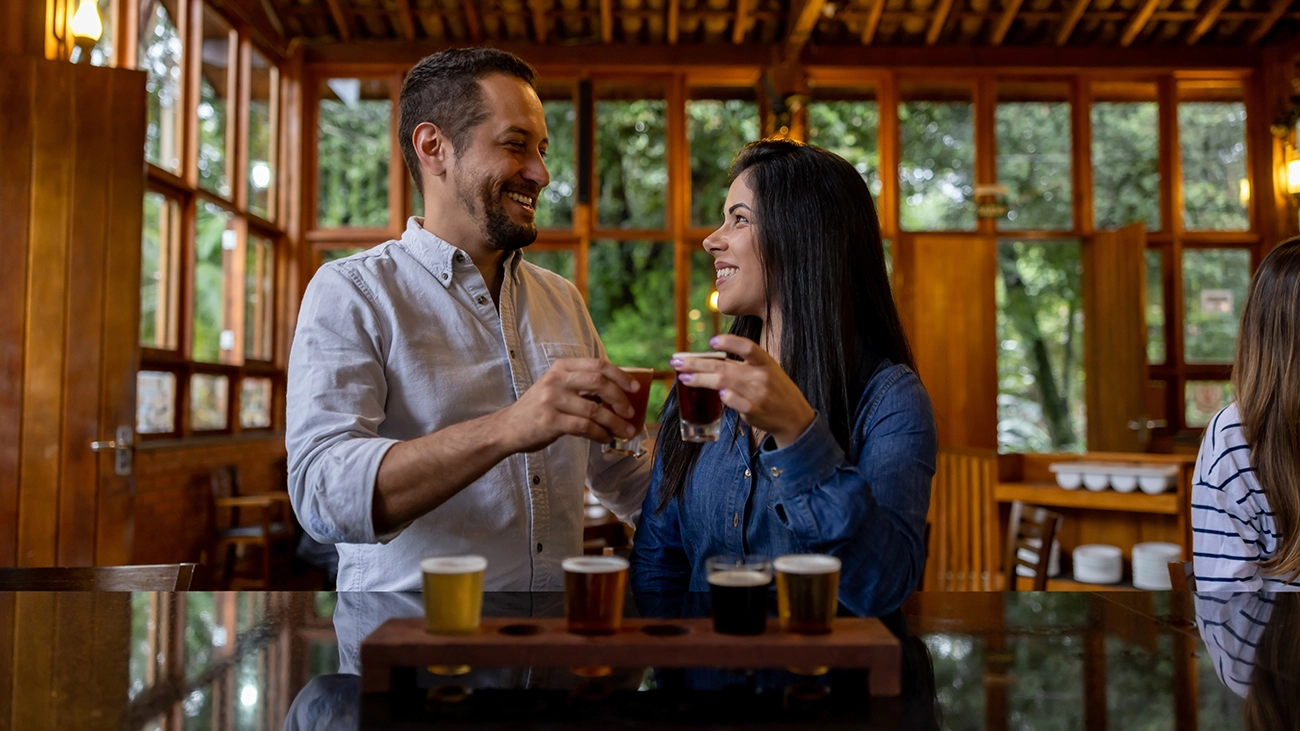 A couple making a cheers gesture with drinks at a craft beer tasting