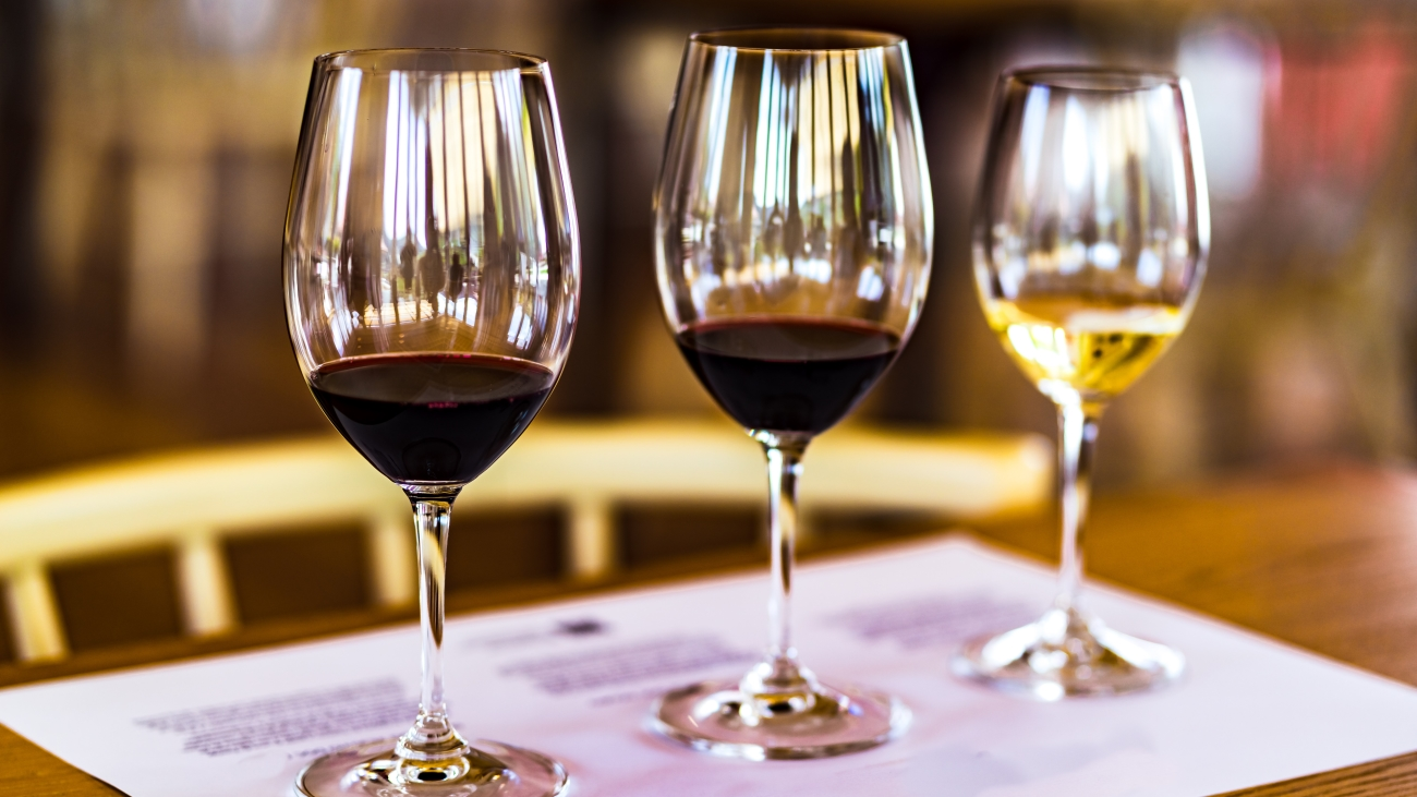 Three wine glasses with red and white wine on a table