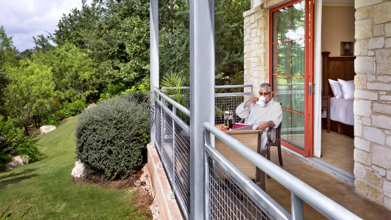 A person sitting on the balcony sipping from a mug in the morning